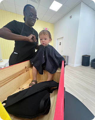 Person cutting a child's hair in a salon setting