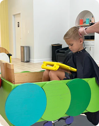 Child getting a haircut in a modern salon with colorful chair design.