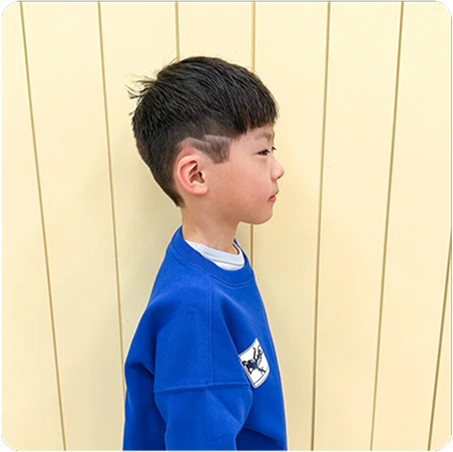 Child wearing a blue sweatshirt with a logo against a light wooden panel background