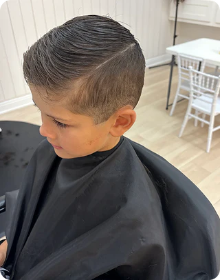 Child getting a haircut with a modern styled haircut in a salon setting.