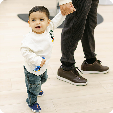 Child holding an adult's hand on a light-colored floor