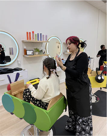 Woman getting a haircut in a salon with mirrors and hair products on shelves.