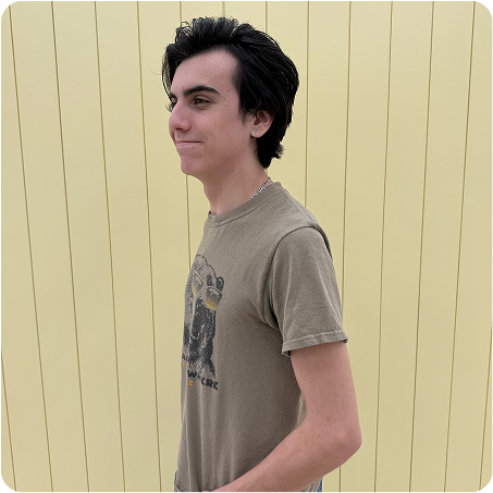 Man wearing a brown t-shirt with a graphic design against a beige wooden background
