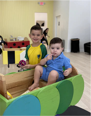 Two children playing in a colorful play area with toys.