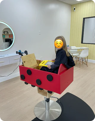 Person sitting in a red and black chair with a yellow tray in a room with a mirror and table.